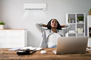 Happy young businesswoman working in home office with air conditioning