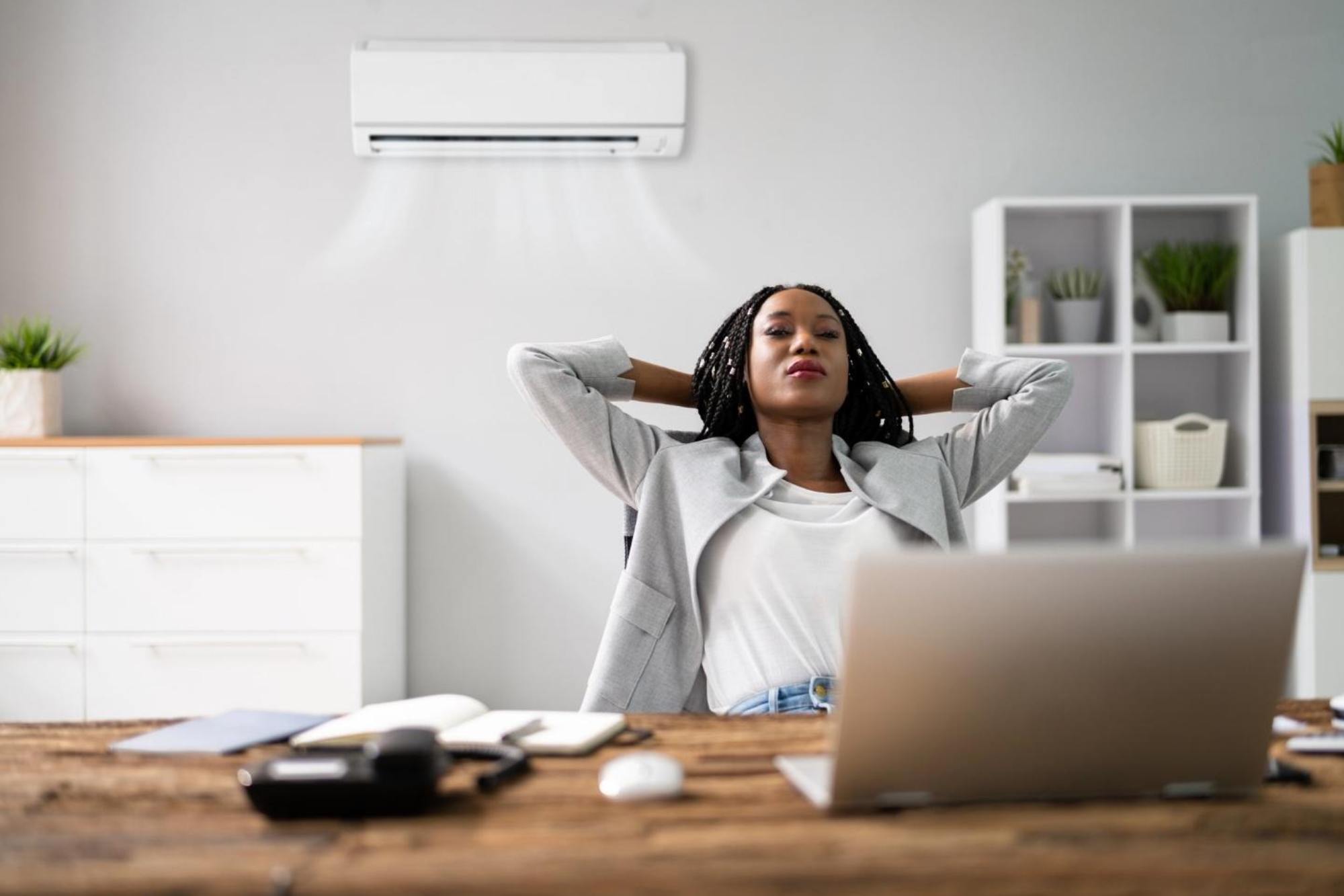 Happy young businesswoman working in home office with air conditioning